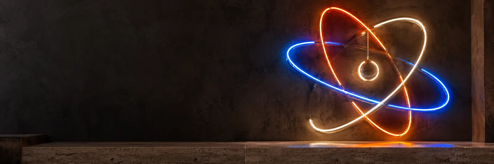 Koyu duvarda turuncu, beyaz ve mavi neon tüplerle çizilmiş atom tasarımı